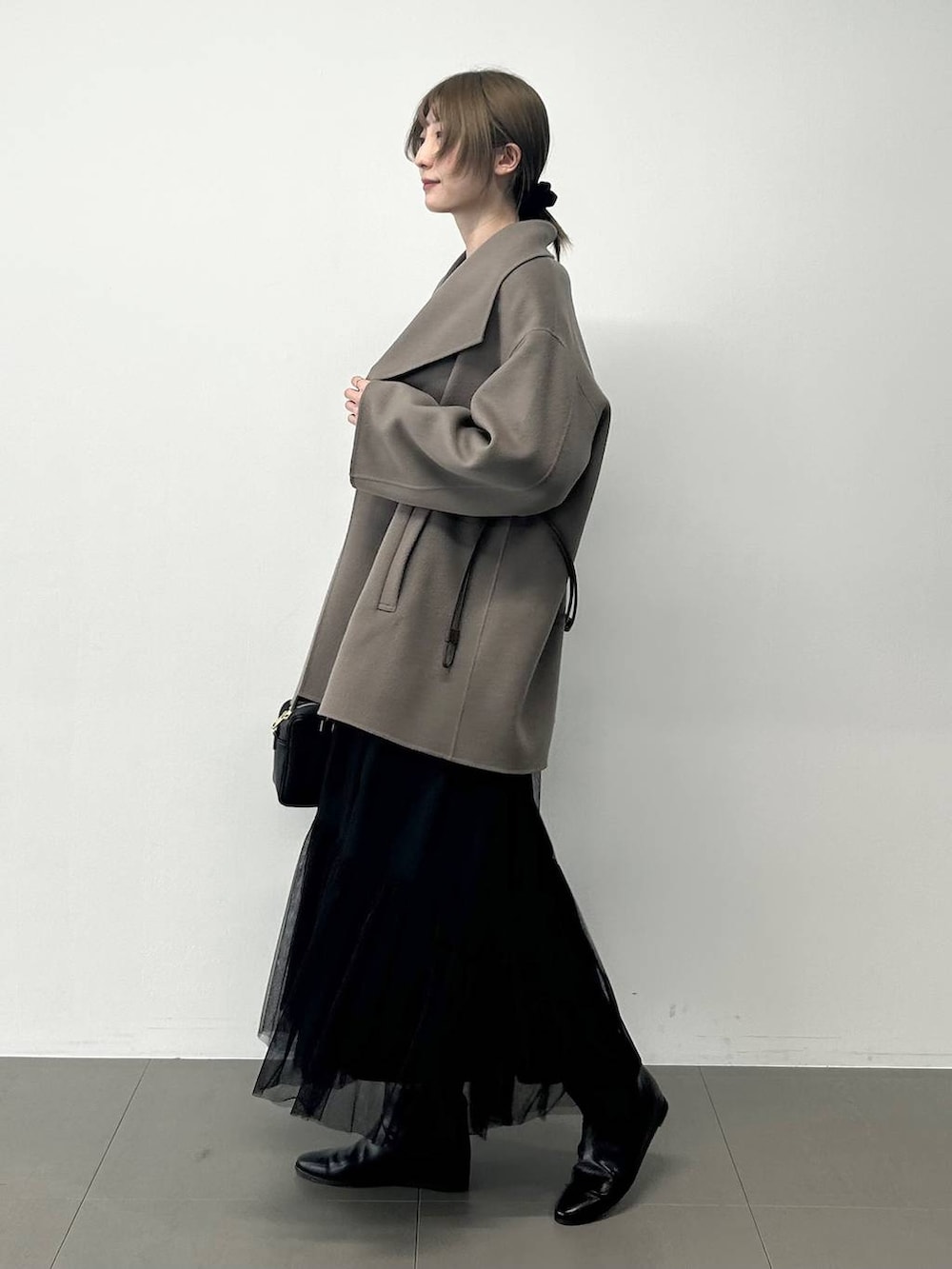 ブラック系のボストンバッグ、ブラウン系のピーコート、ブラック系のニット/セーターを着用したレディースの冬コーディネートの2枚目の写真