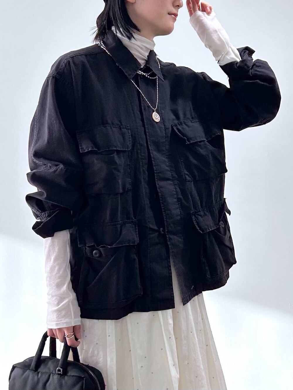 ブラック系のミリタリージャケット、ホワイト系のTシャツ/カットソー、ホワイト系のスカートを着用したレディースの冬コーディネートの5枚目の写真