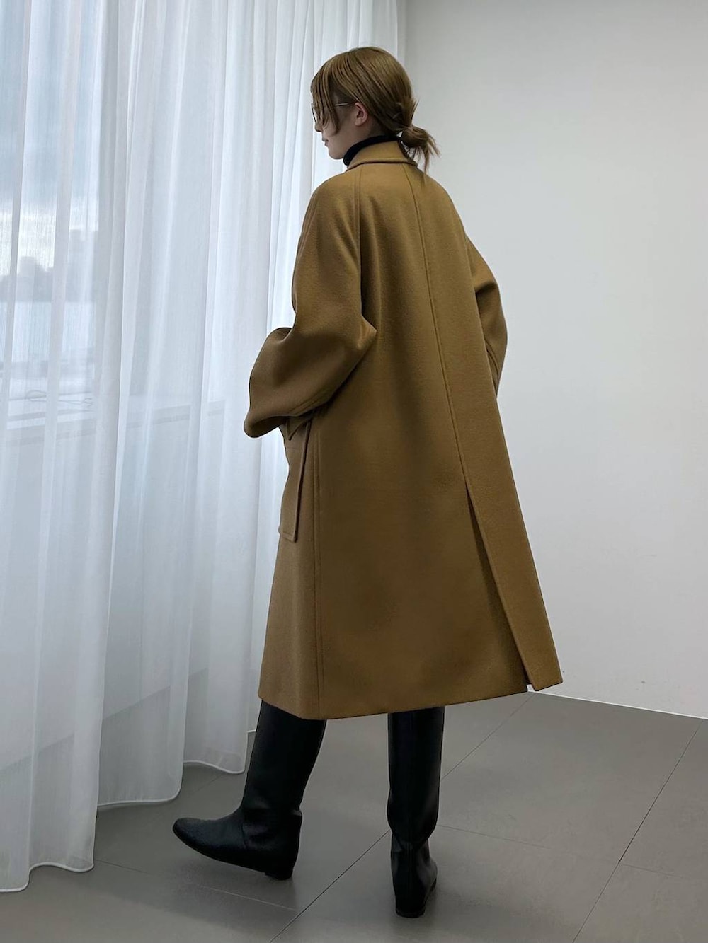 イエロー系のステンカラーコート、ブラック系のボストンバッグ、ブラック系のニット/セーターを着用したレディースの秋コーディネートの2枚目の写真