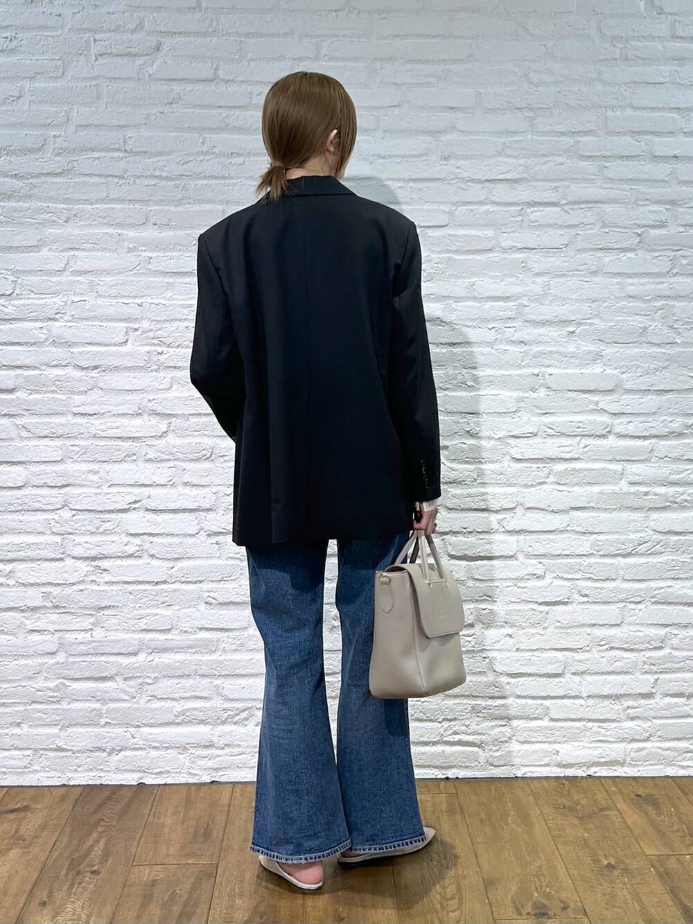 ベージュ系のパンプス、ブラック系のテーラードジャケット、ブルー系のデニムパンツを着用したレディースの冬コーディネートの3枚目の写真