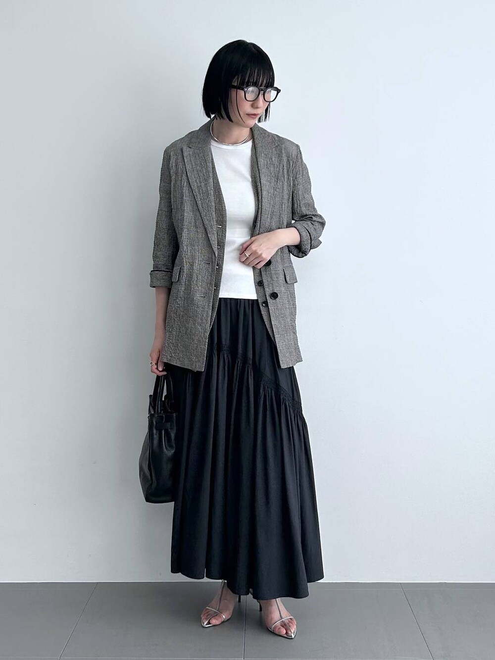 ブラック系のハンドバッグ、ブラック系のテーラードジャケット、ブラック系のベストを着用したレディースの冬コーディネートの4枚目の写真