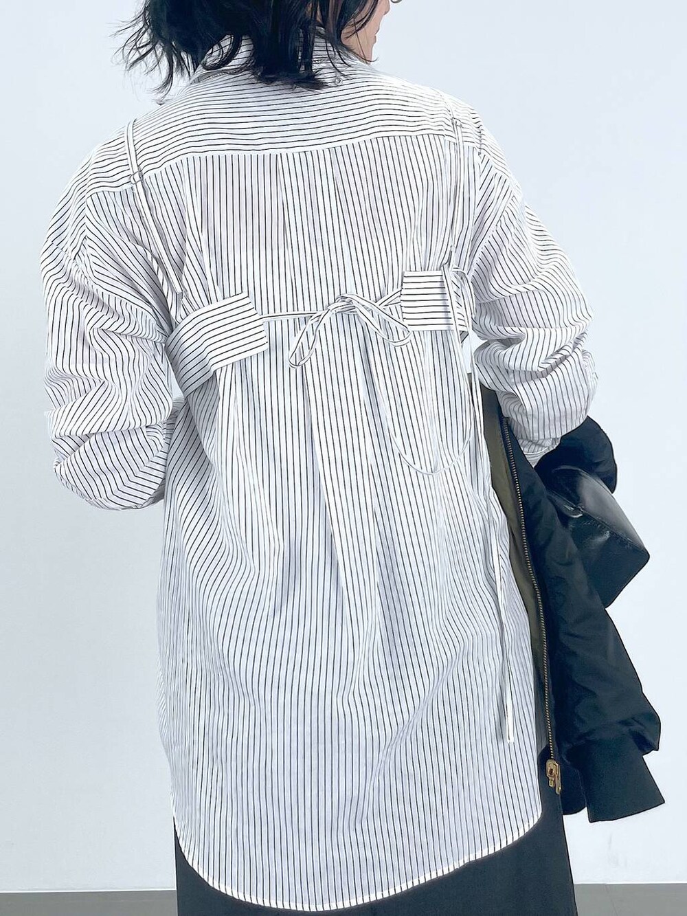 グレー系のワンピース、レッド系のパンプス、ブラック系のMA-1を着用したレディースの秋コーディネートの5枚目の写真