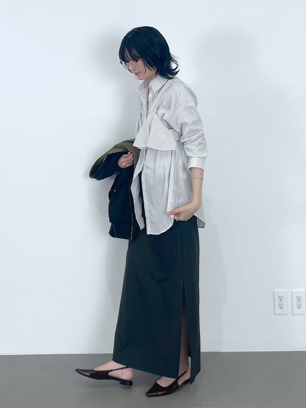 グレー系のワンピース、レッド系のパンプス、ブラック系のMA-1を着用したレディースの秋コーディネートの2枚目の写真