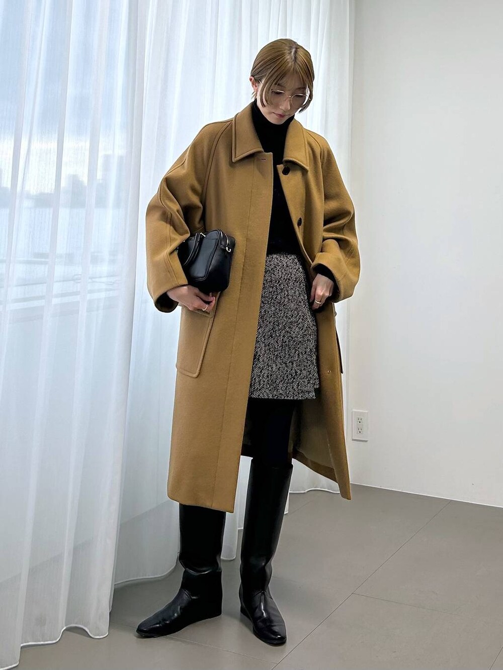 イエロー系のステンカラーコート、ブラック系のボストンバッグ、ブラック系のニット/セーターを着用したレディースの秋コーディネートの4枚目の写真