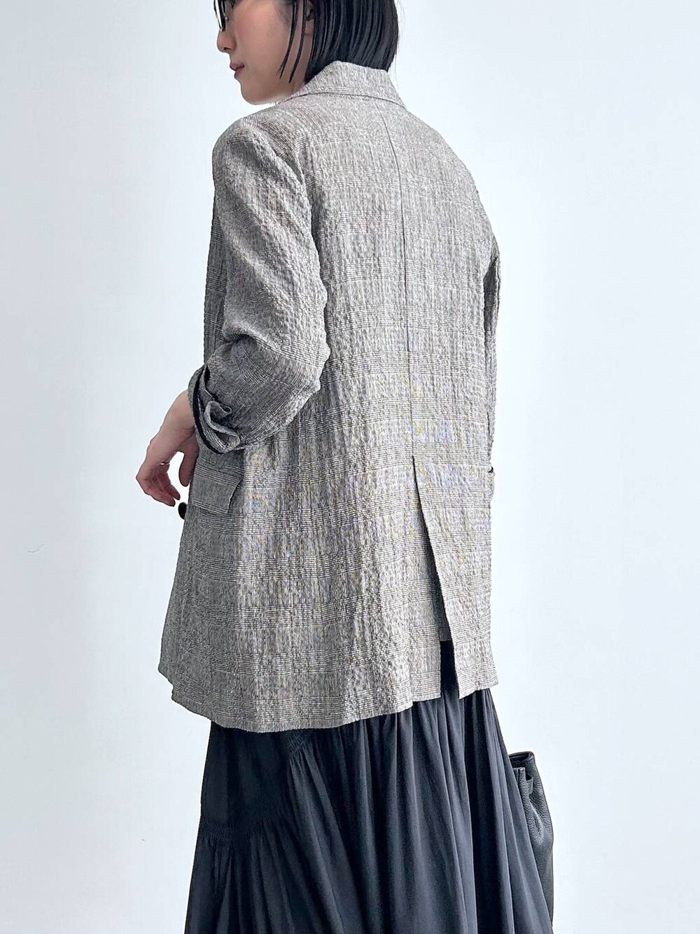 ブラック系のハンドバッグ、ブラック系のテーラードジャケット、ブラック系のベストを着用したレディースの冬コーディネートの3枚目の写真