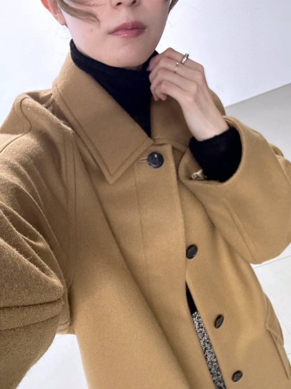 イエロー系のステンカラーコート、ブラック系のボストンバッグ、ブラック系のニット/セーターを着用したレディースの秋コーディネートの5枚目の写真