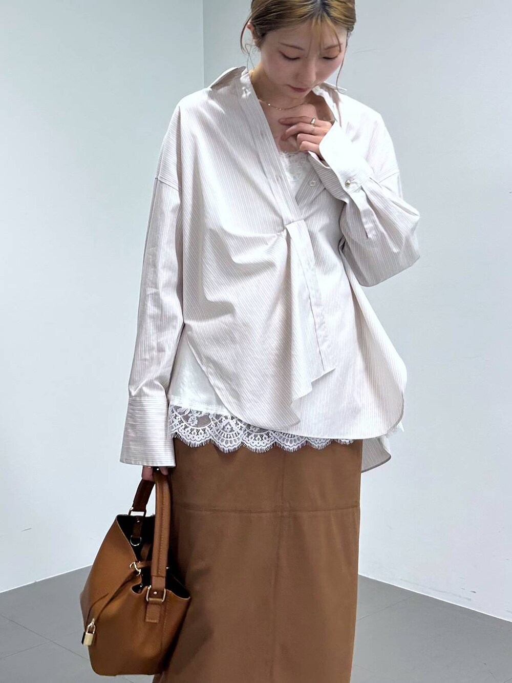 イエロー系のスカート、ベージュ系のシャツ/ブラウス、ブラウン系のショルダーバッグを着用したレディースの冬コーディネートの4枚目の写真