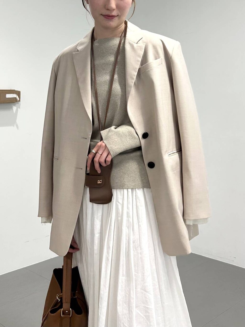 ベージュ系のパンプス、ベージュ系のテーラードジャケット、ホワイト系のスカートを着用したレディースの冬コーディネートの3枚目の写真