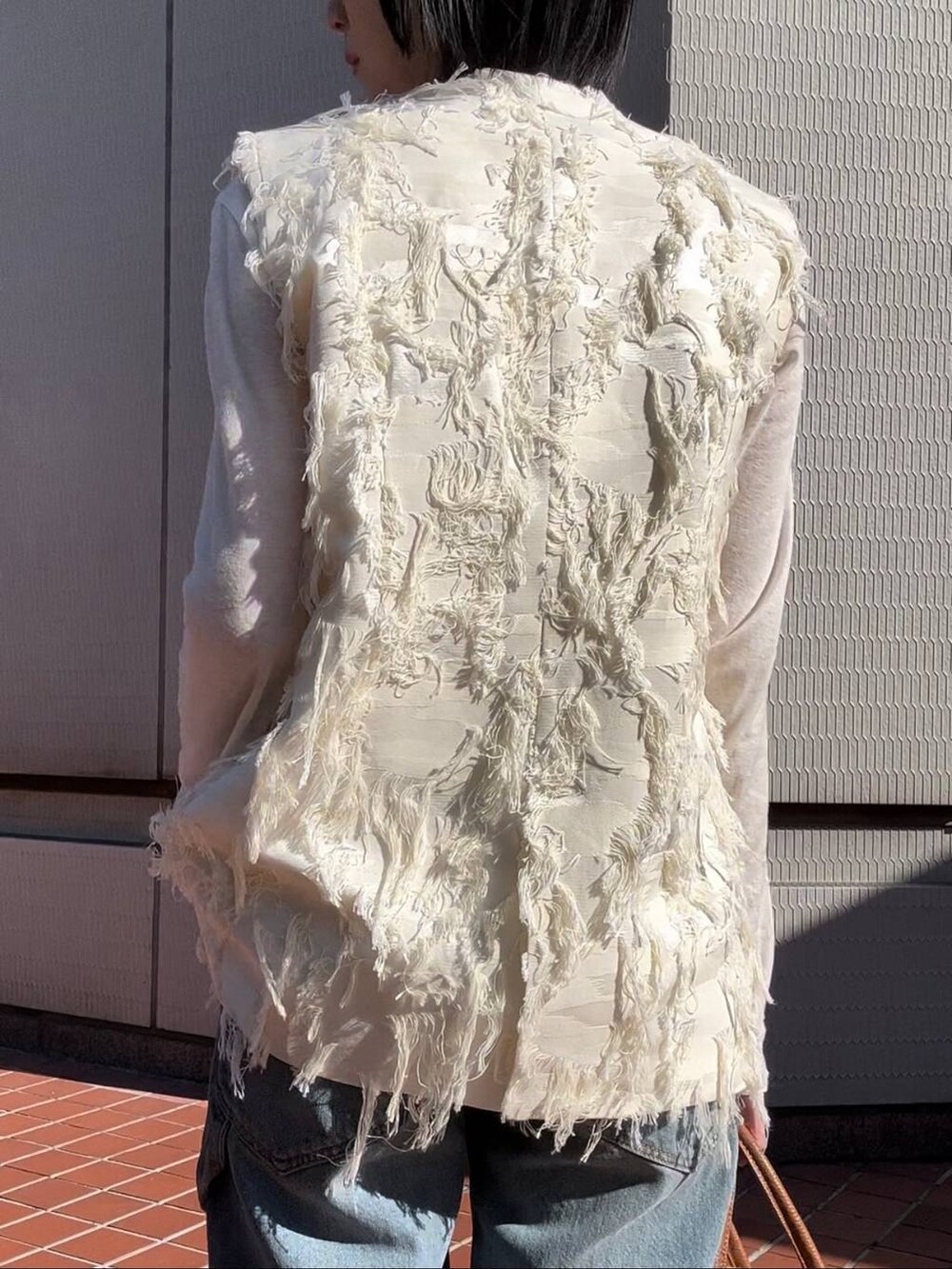 ホワイト系のTシャツ/カットソー、ホワイト系のベスト、ブルー系のデニムパンツを着用したレディースの冬コーディネートの5枚目の写真