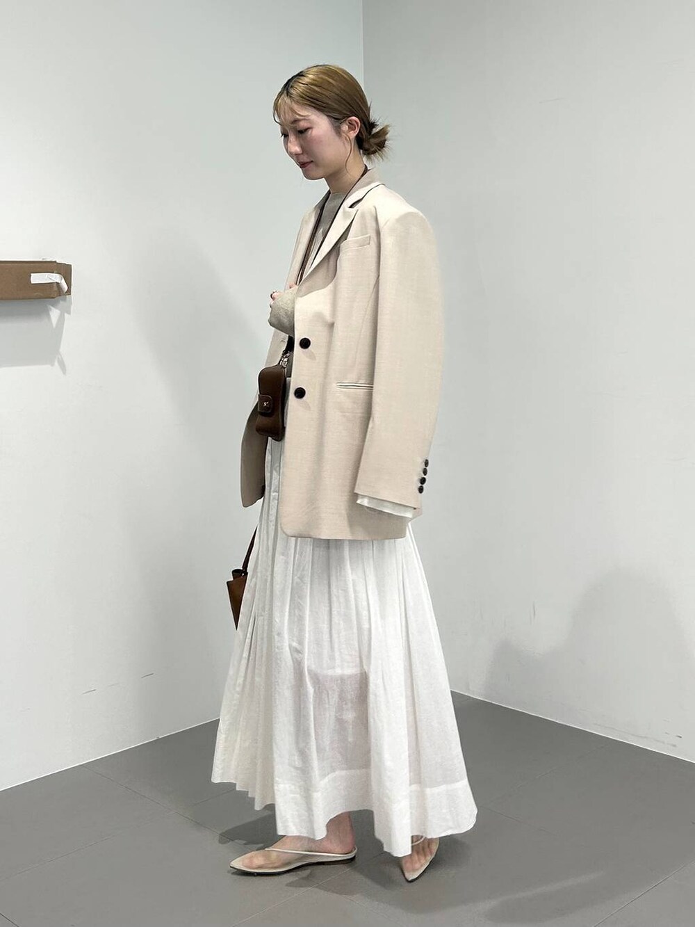 ベージュ系のパンプス、ベージュ系のテーラードジャケット、ホワイト系のスカートを着用したレディースの冬コーディネートの2枚目の写真