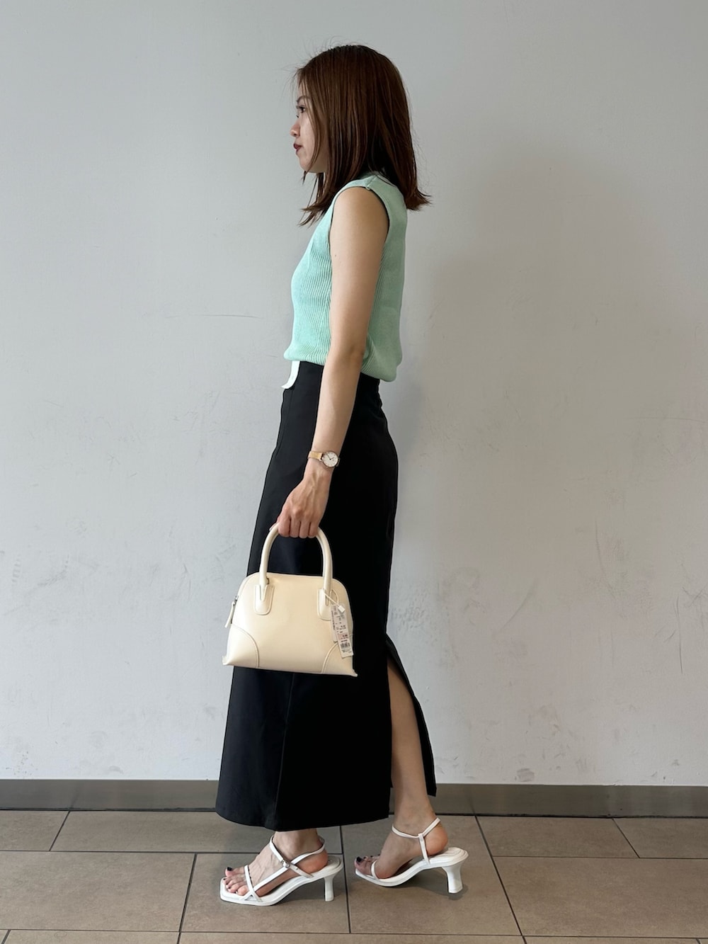 グリーン系のニット/セーター、グレー系のスカート、ホワイト系のサンダルを着用したレディースの夏コーディネートの3枚目の写真