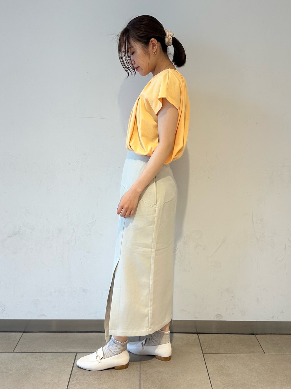 オレンジ系のTシャツ/カットソー、ベージュ系のスカート、ホワイト系のローファーを着用したレディースの夏コーディネートの2枚目の写真