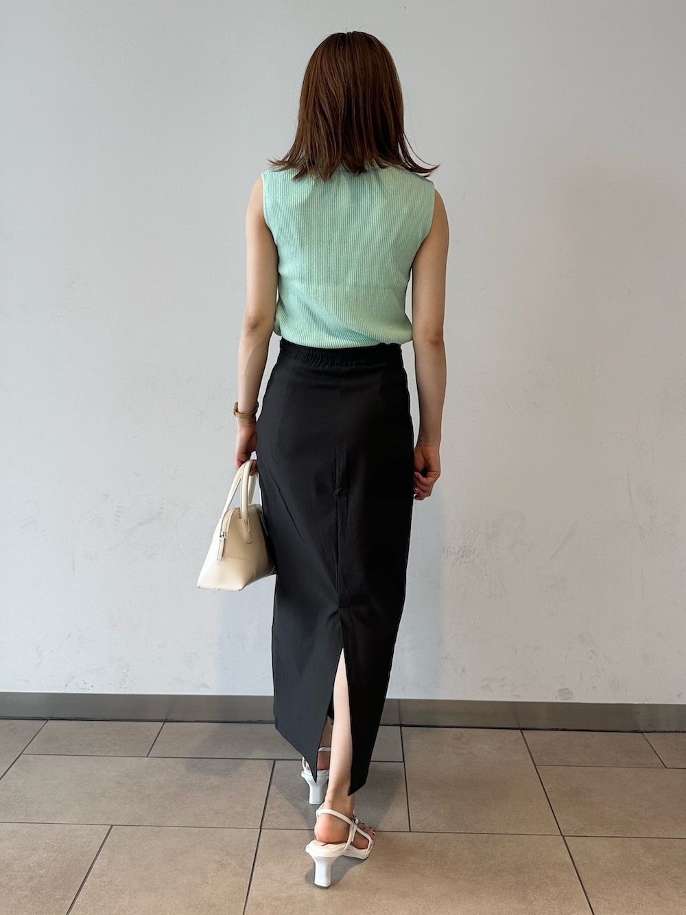 グリーン系のニット/セーター、グレー系のスカート、ホワイト系のサンダルを着用したレディースの夏コーディネートの2枚目の写真