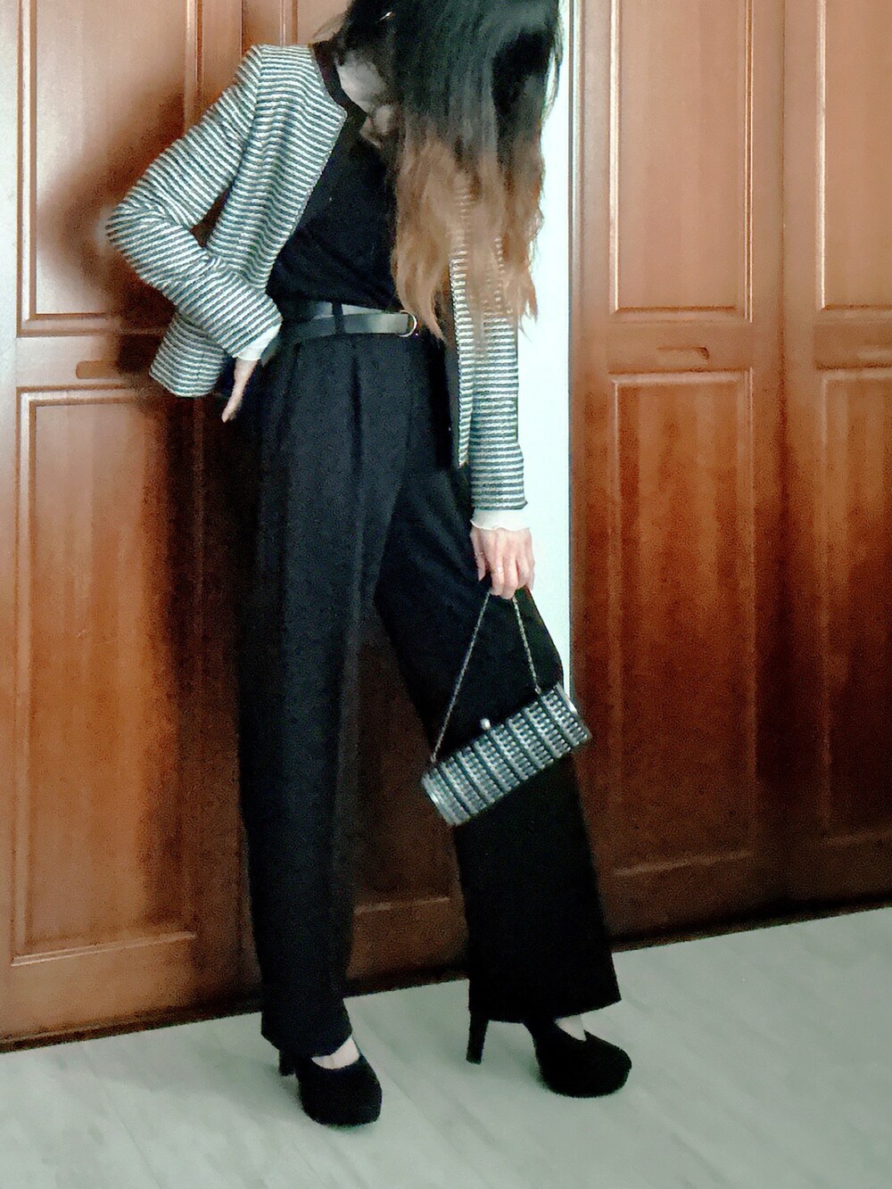 ブラック系のスーツセット、グレー系のクラッチバッグ、ブラック系のベルトを着用したレディースの春コーディネートの2枚目の写真