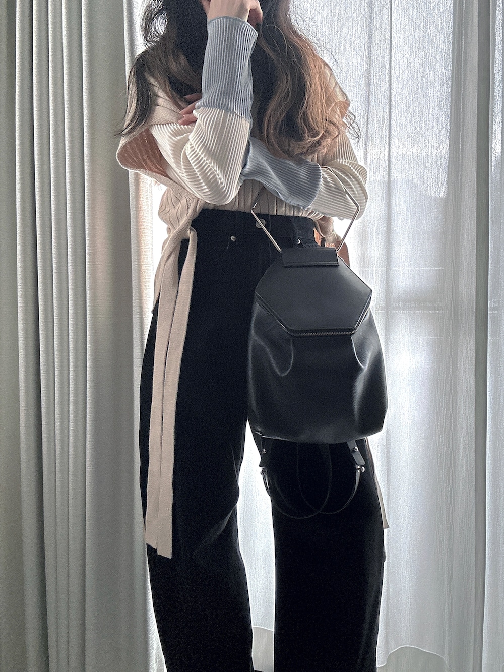 ブラック系のデニムパンツ、ホワイト系のTシャツ/カットソー、ベージュ系のベストを着用したレディースの春コーディネートの2枚目の写真