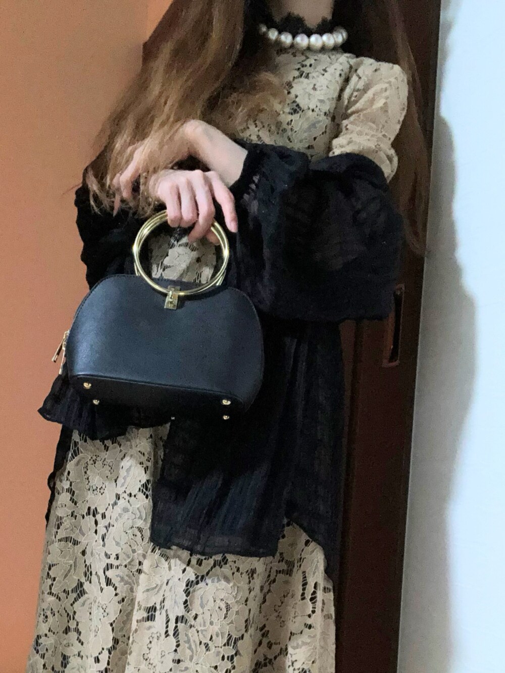 ベージュ系のドレス、ブラック系のパンプス、ブラック系のハンドバッグを着用したレディースの冬コーディネートの2枚目の写真