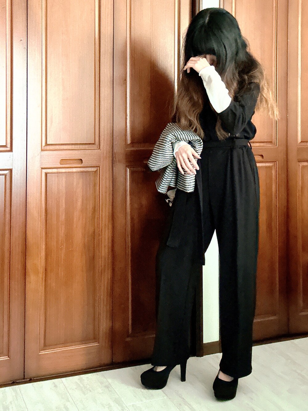 ブラック系のスーツセット、グレー系のクラッチバッグ、ブラック系のベルトを着用したレディースの春コーディネートの4枚目の写真