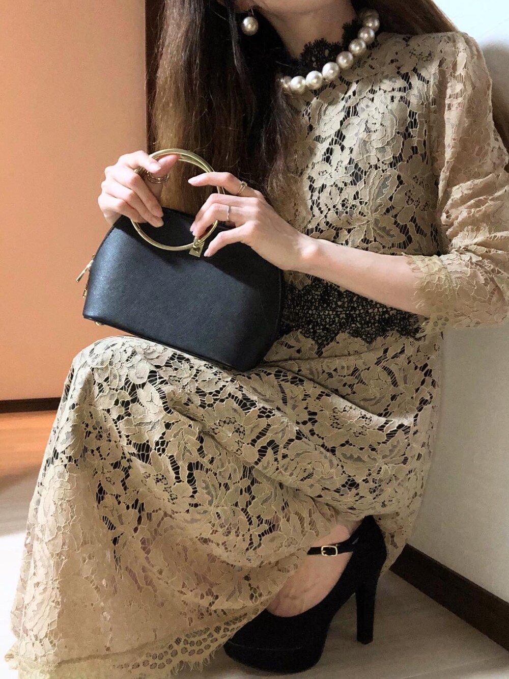 ベージュ系のドレス、ブラック系のパンプス、ブラック系のハンドバッグを着用したレディースの冬コーディネートの5枚目の写真