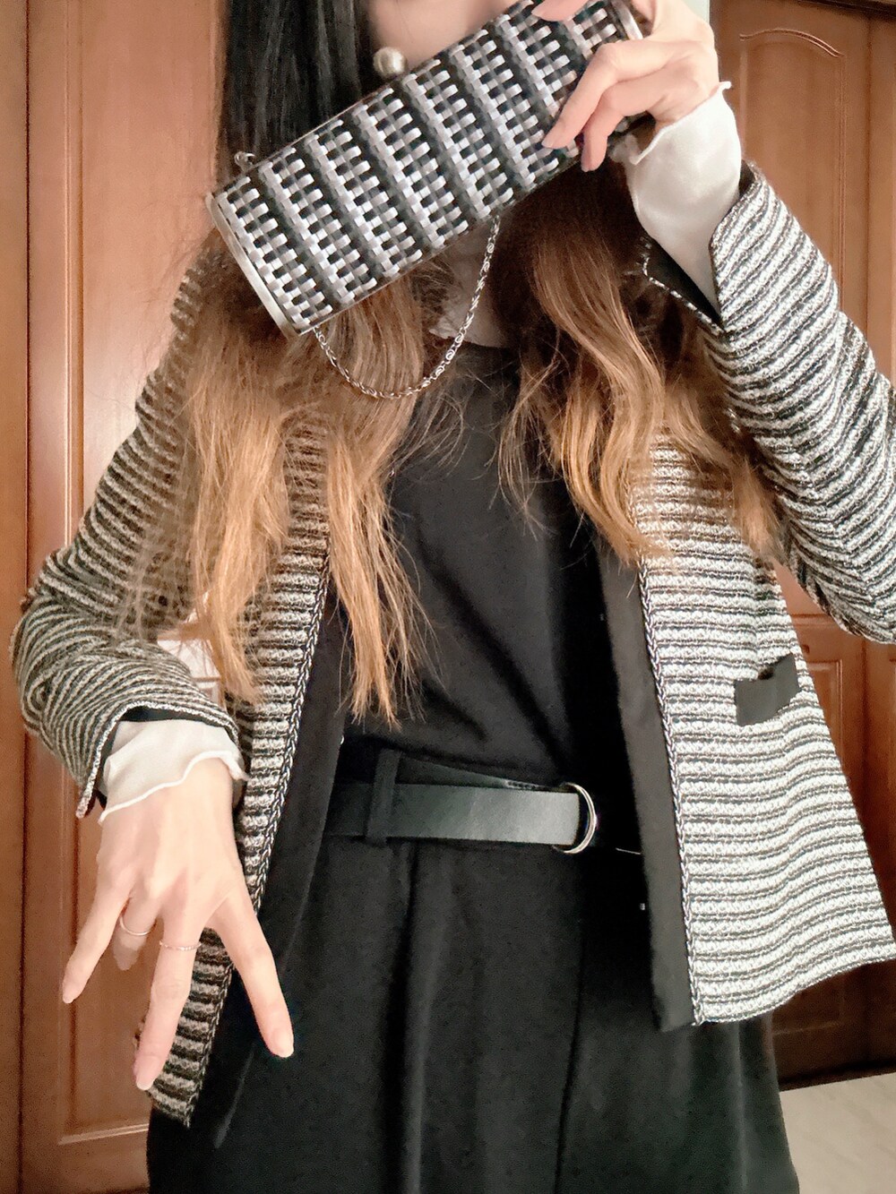 ブラック系のスーツセット、グレー系のクラッチバッグ、ブラック系のベルトを着用したレディースの春コーディネートの3枚目の写真