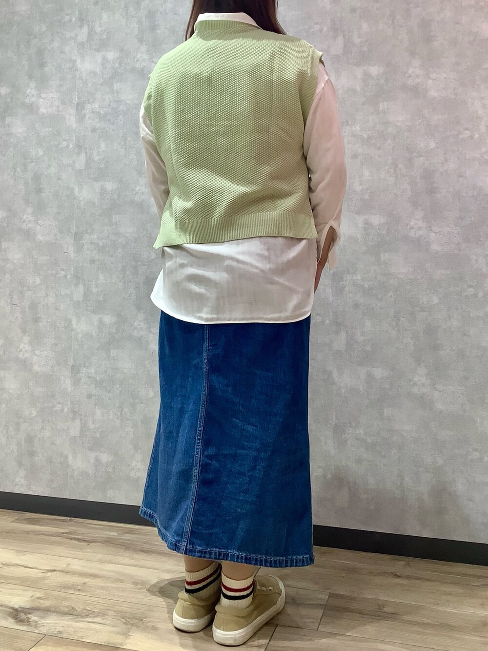 グリーン系のベスト、ブルー系のデニムスカート、ホワイト系のシャツ/ブラウスを着用したレディースの春コーディネートの3枚目の写真