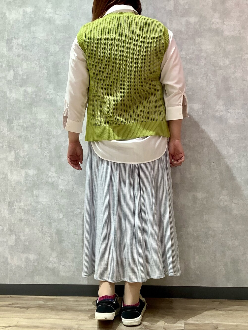 イエロー系のベスト、ブルー系のスカート、ホワイト系のシャツ/ブラウスを着用したレディースの春コーディネートの3枚目の写真