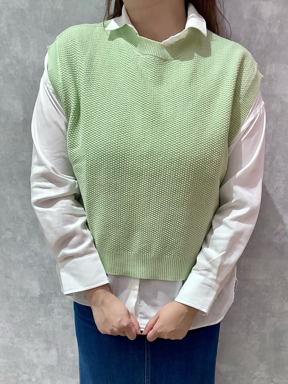 グリーン系のベスト、ブルー系のデニムスカート、ホワイト系のシャツ/ブラウスを着用したレディースの春コーディネートの2枚目の写真