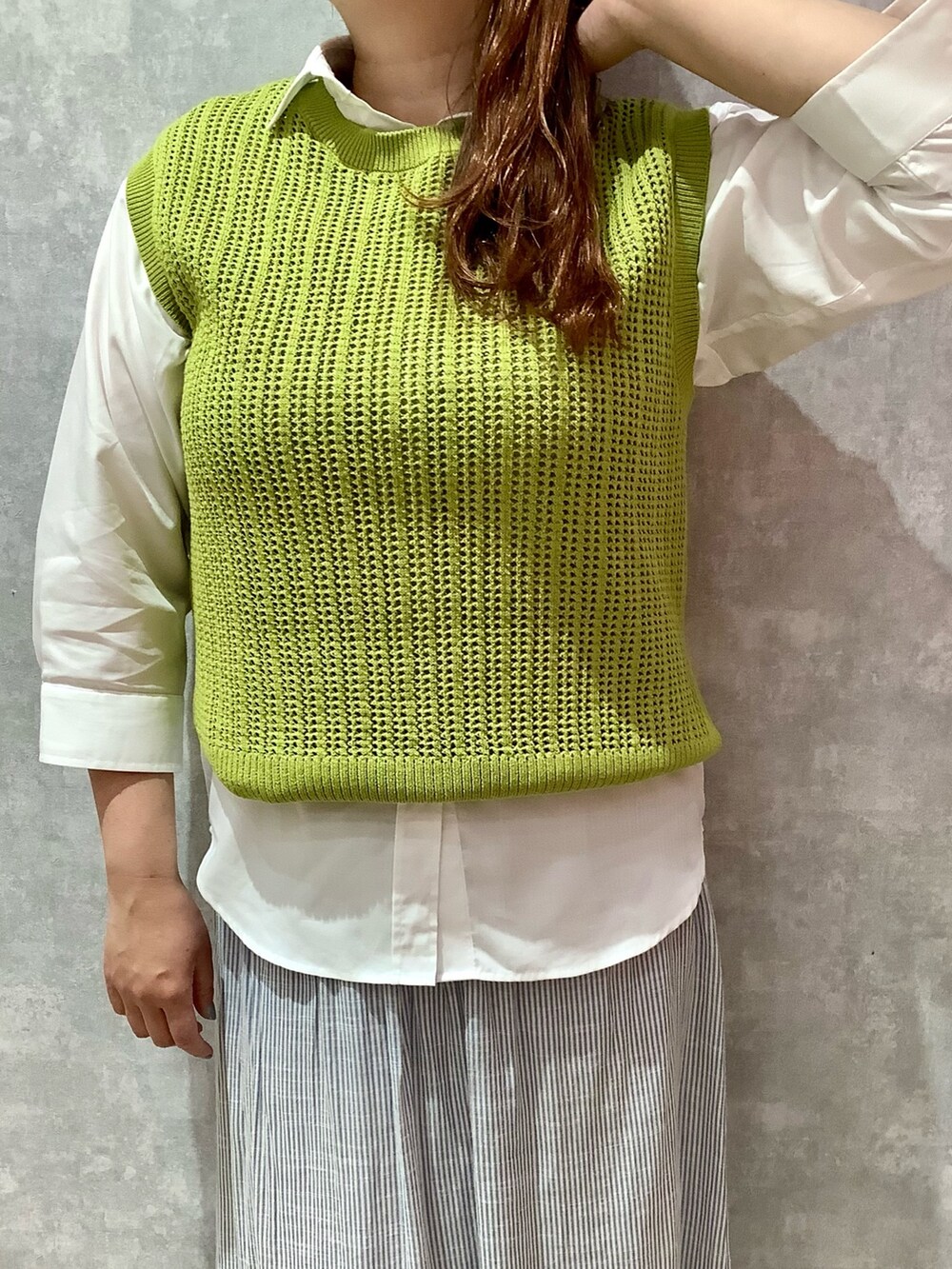 イエロー系のベスト、ブルー系のスカート、ホワイト系のシャツ/ブラウスを着用したレディースの春コーディネートの2枚目の写真