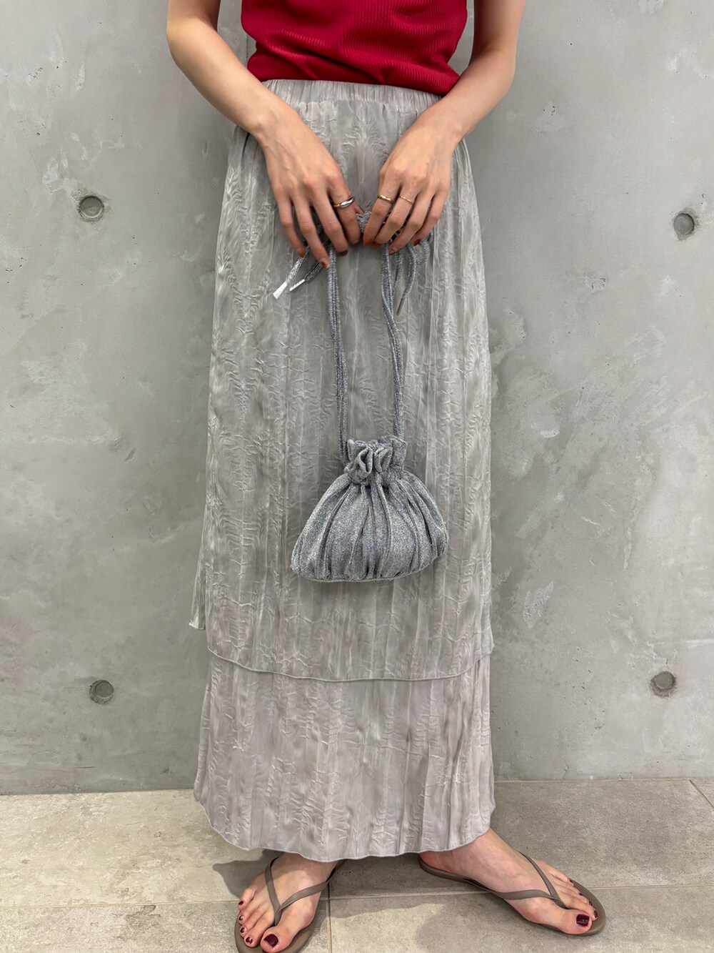 レッド系のタンクトップ、グレー系のスカート、シルバー系のショルダーバッグを着用したレディースの夏コーディネートの5枚目の写真