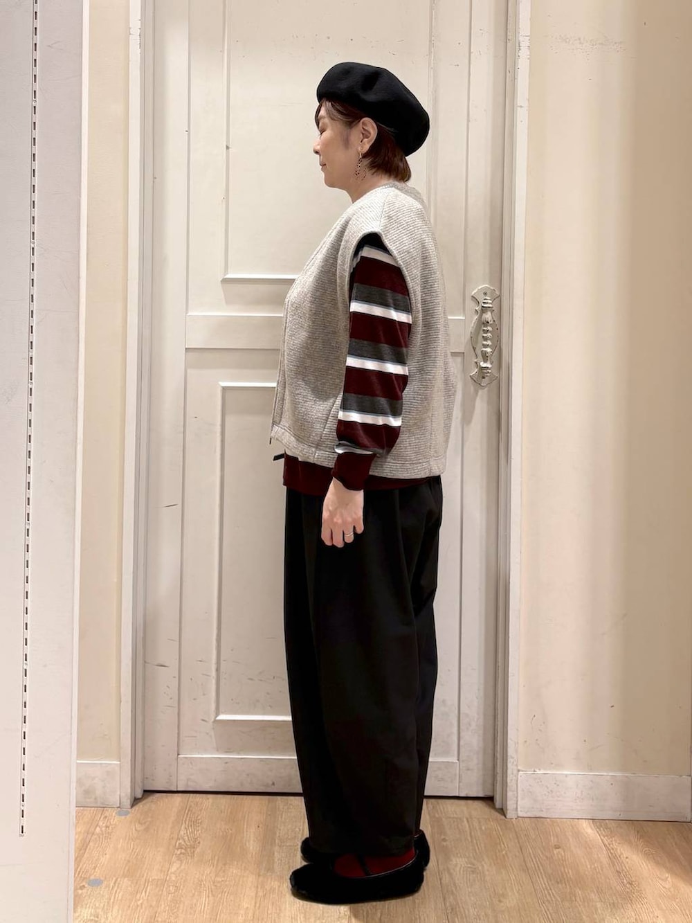 ベージュ系のベスト、レッド系のニット/セーター、ブラック系のパンプスを着用したレディースの秋コーディネートの2枚目の写真