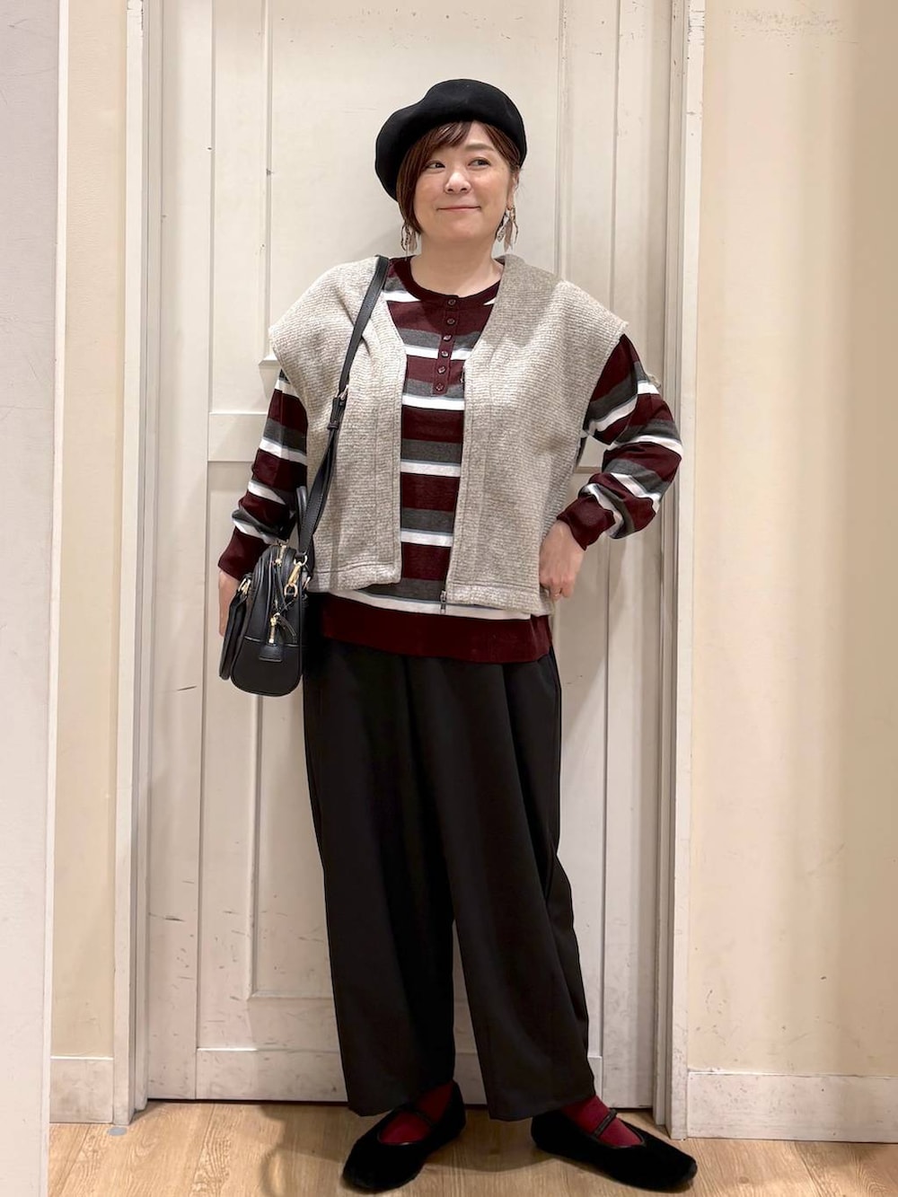 ベージュ系のベスト、レッド系のニット/セーター、ブラック系のパンプスを着用したレディースの秋コーディネートの7枚目の写真