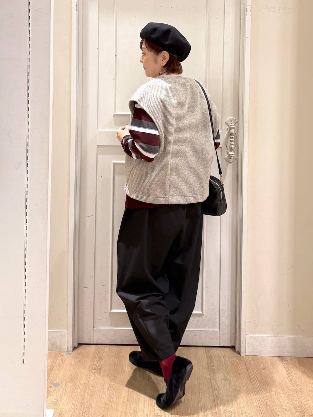 ベージュ系のベスト、レッド系のニット/セーター、ブラック系のパンプスを着用したレディースの秋コーディネートの3枚目の写真