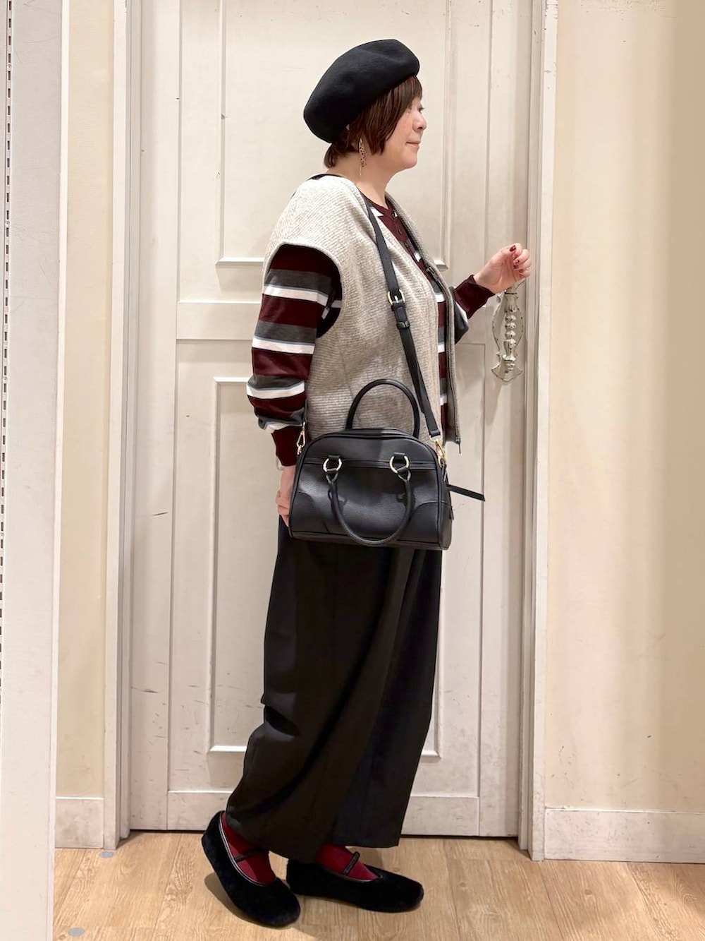 ベージュ系のベスト、レッド系のニット/セーター、ブラック系のパンプスを着用したレディースの秋コーディネートの6枚目の写真