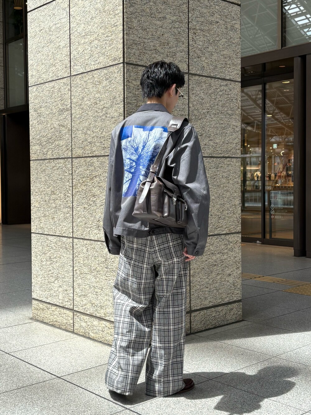 グレー系のブルゾン、ブラウン系のショルダーバッグを着用したメンズの春コーディネートの3枚目の写真