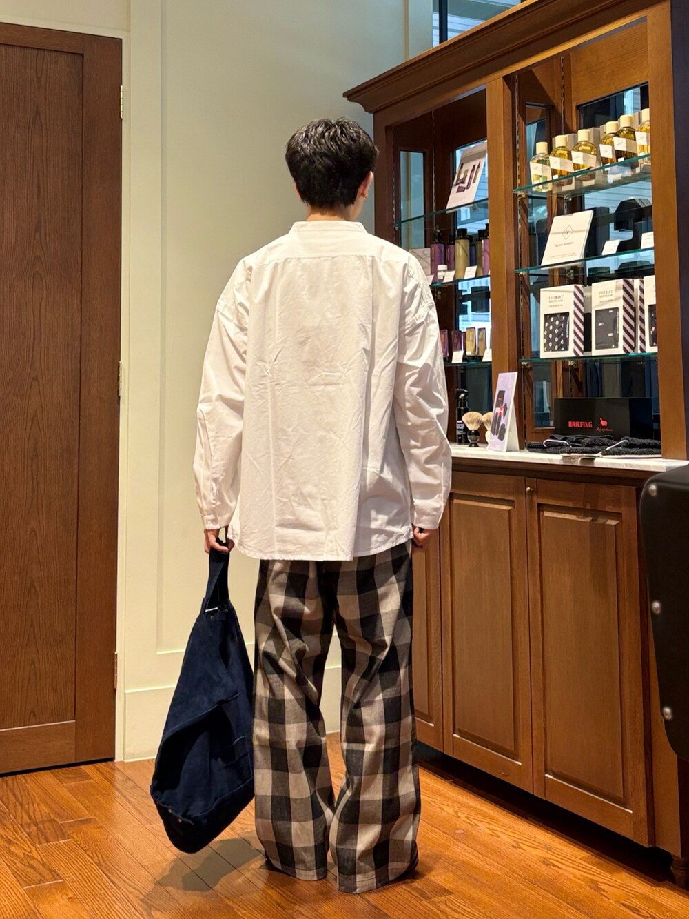 ホワイト系のシャツ/ブラウス、ホワイト系のパンツ、ブルー系のトートバッグを着用したメンズの春コーディネートの3枚目の写真