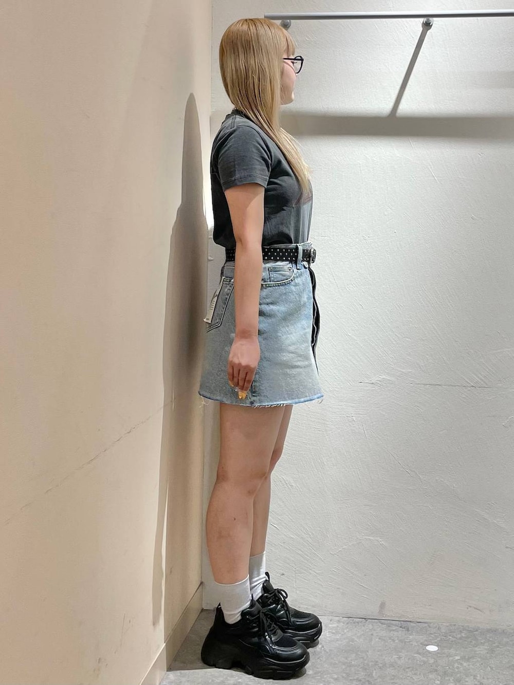 ブラック系のスニーカー、ブルー系のデニムスカート、グレー系のTシャツ/カットソーを着用したレディースの夏コーディネートの2枚目の写真