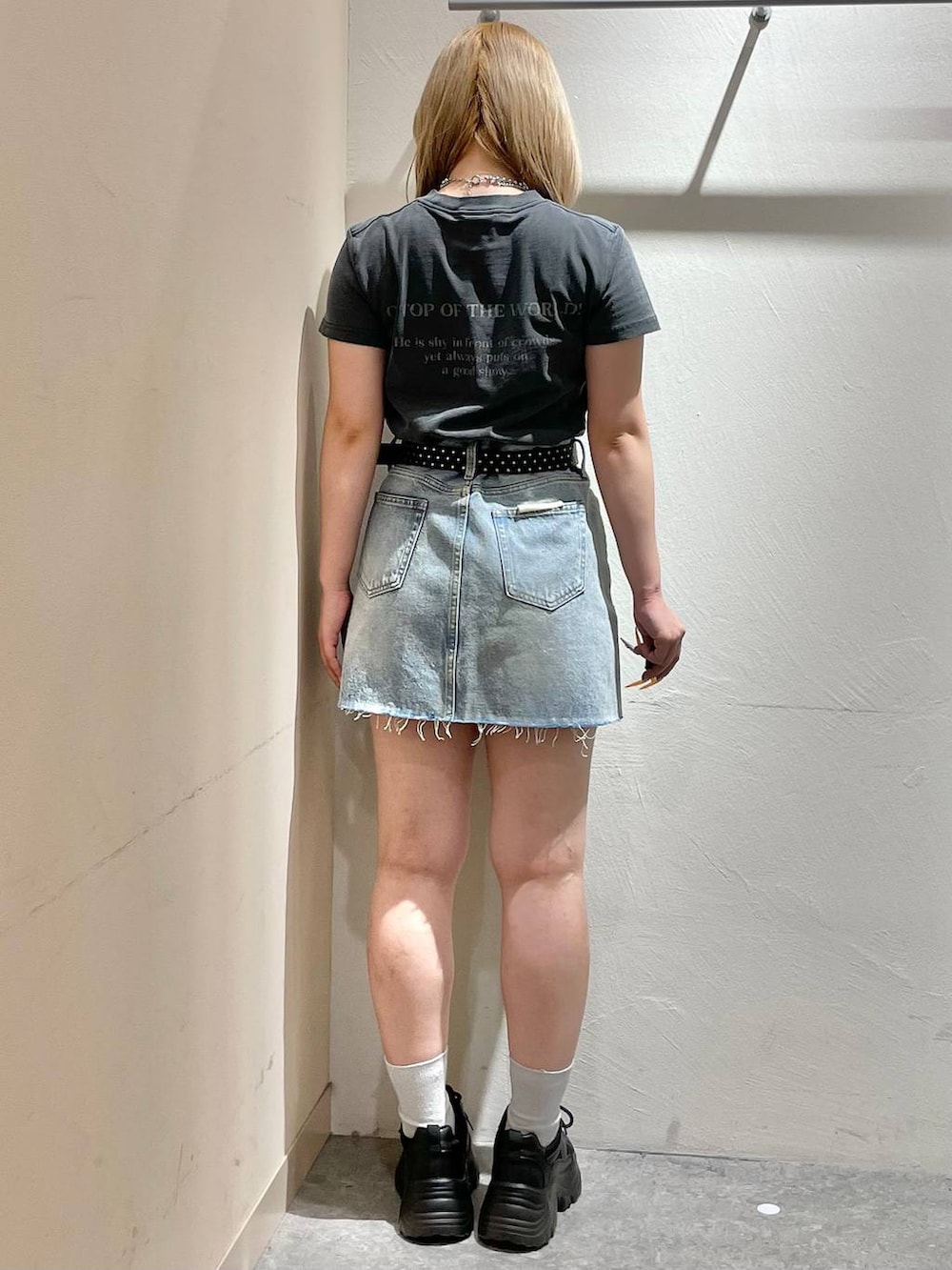 ブラック系のスニーカー、ブルー系のデニムスカート、グレー系のTシャツ/カットソーを着用したレディースの夏コーディネートの3枚目の写真