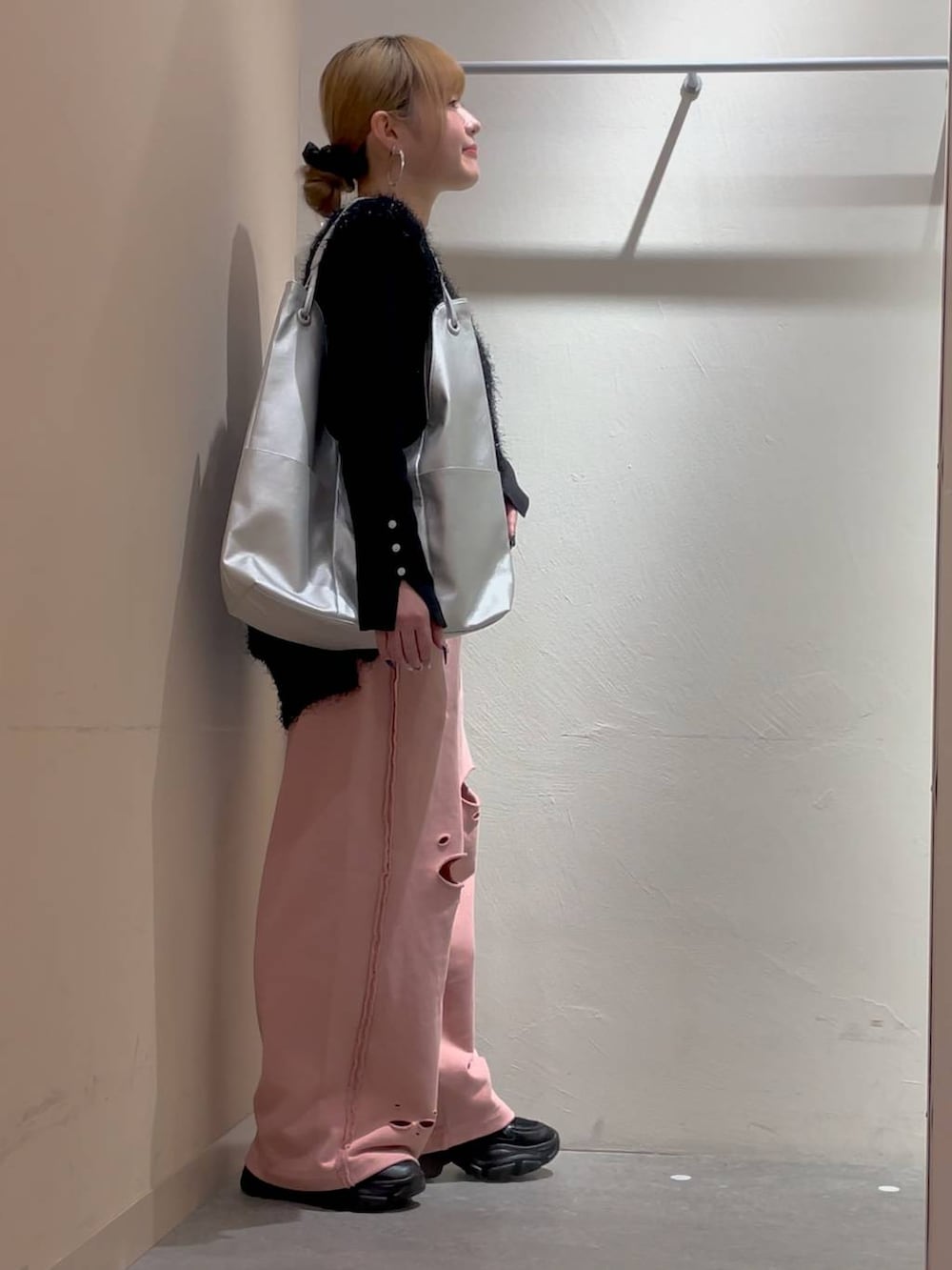 シルバー系のトートバッグ、ブラック系のニット/セーター、ピンク系のスウェットパンツを着用したレディースの冬コーディネートの2枚目の写真
