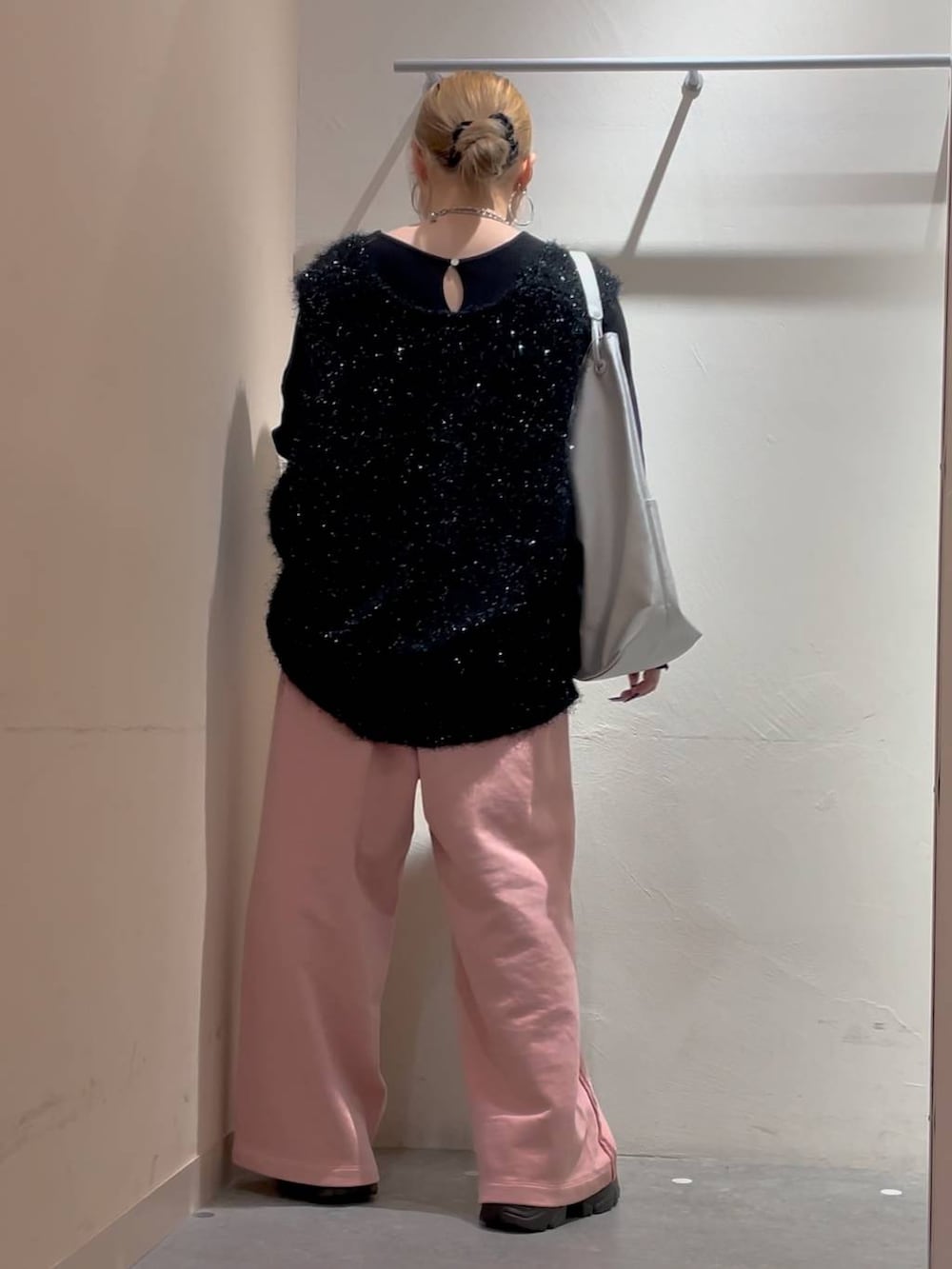 シルバー系のトートバッグ、ブラック系のニット/セーター、ピンク系のスウェットパンツを着用したレディースの冬コーディネートの3枚目の写真