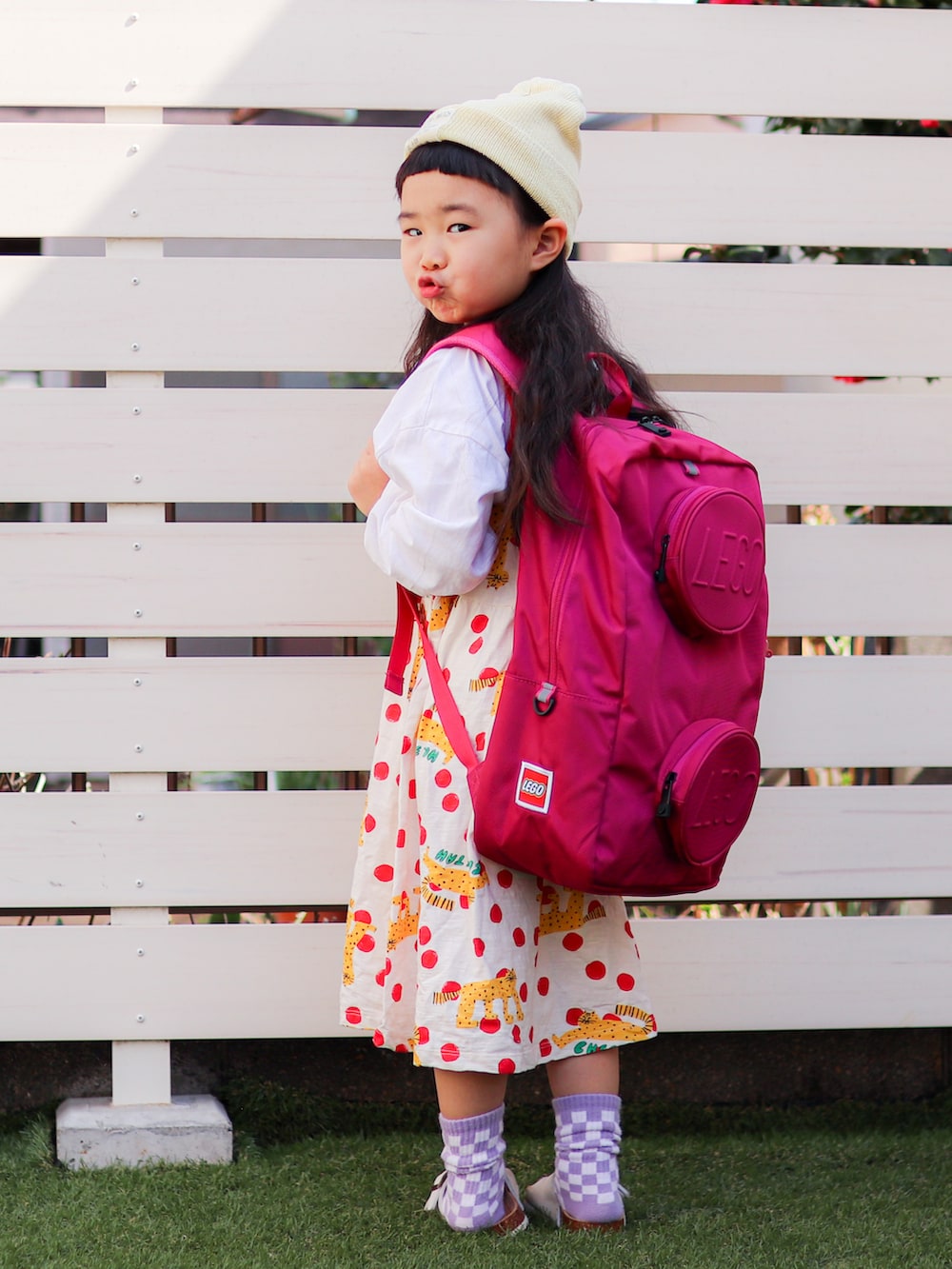 ホワイト系のワンピース、ピンク系のバックパック/リュック、イエロー系のニットキャップ/ビーニーを着用したキッズの春コーディネートの4枚目の写真