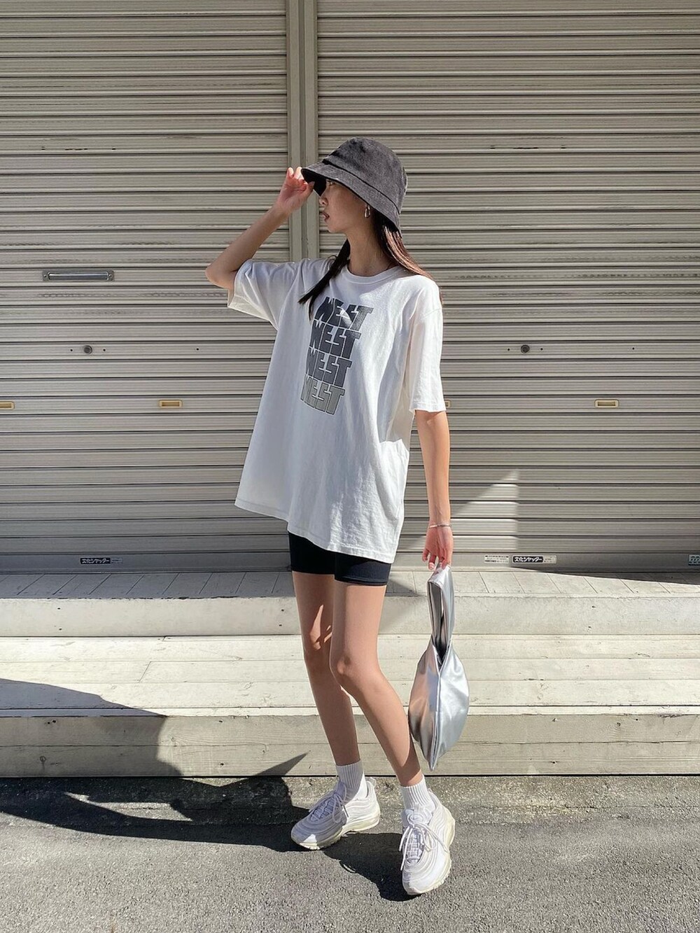 ホワイト系のTシャツ/カットソー、シルバー系のトートバッグ、ホワイト系のスニーカーを着用したレディースの夏コーディネートの2枚目の写真