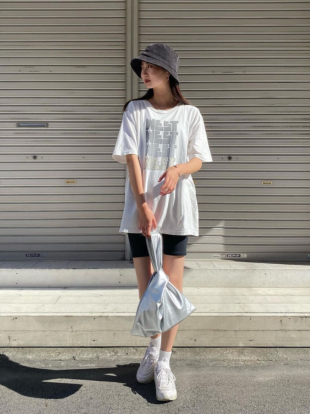 ホワイト系のTシャツ/カットソー、シルバー系のトートバッグ、ホワイト系のスニーカーを着用したレディースの夏コーディネートの3枚目の写真