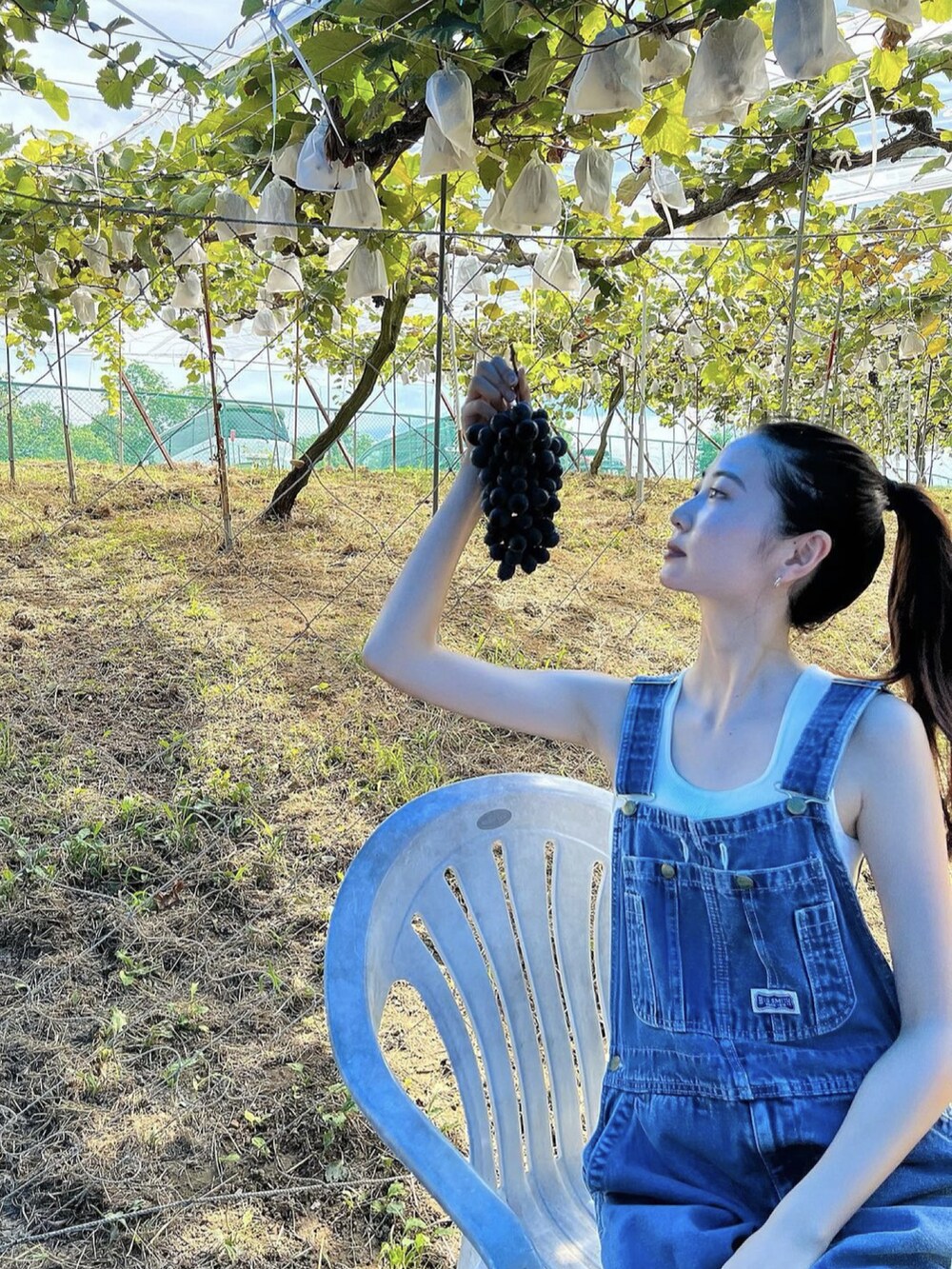 ホワイト系のビーチサンダル、ブルー系のサロペット/オーバーオール、ホワイト系のタンクトップを着用したレディースの夏コーディネートの3枚目の写真