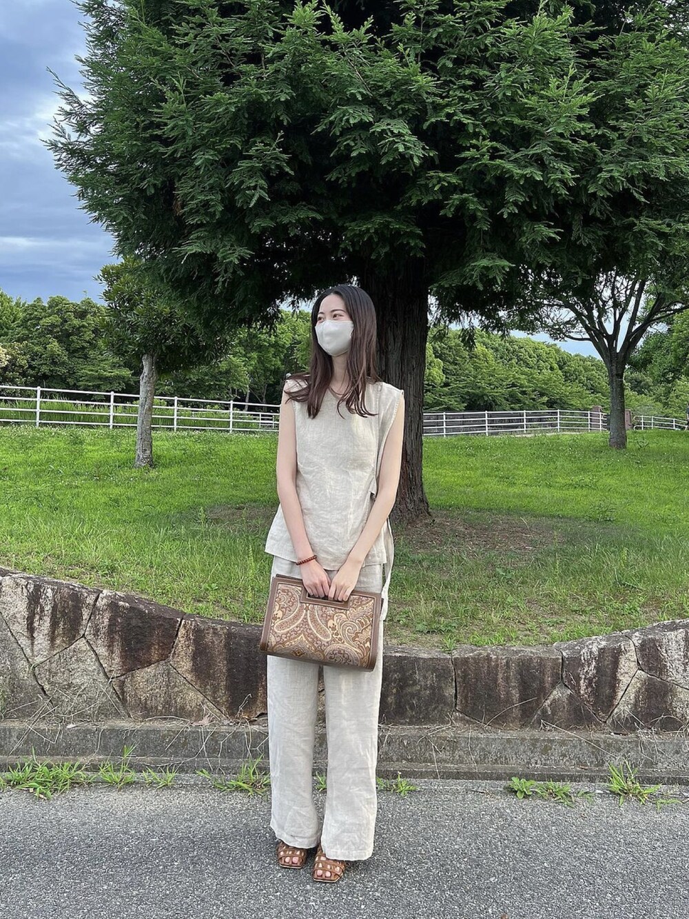 ベージュ系のトップス、ベージュ系のパンツ、ブラウン系のサンダルを着用したレディースの夏コーディネートの3枚目の写真