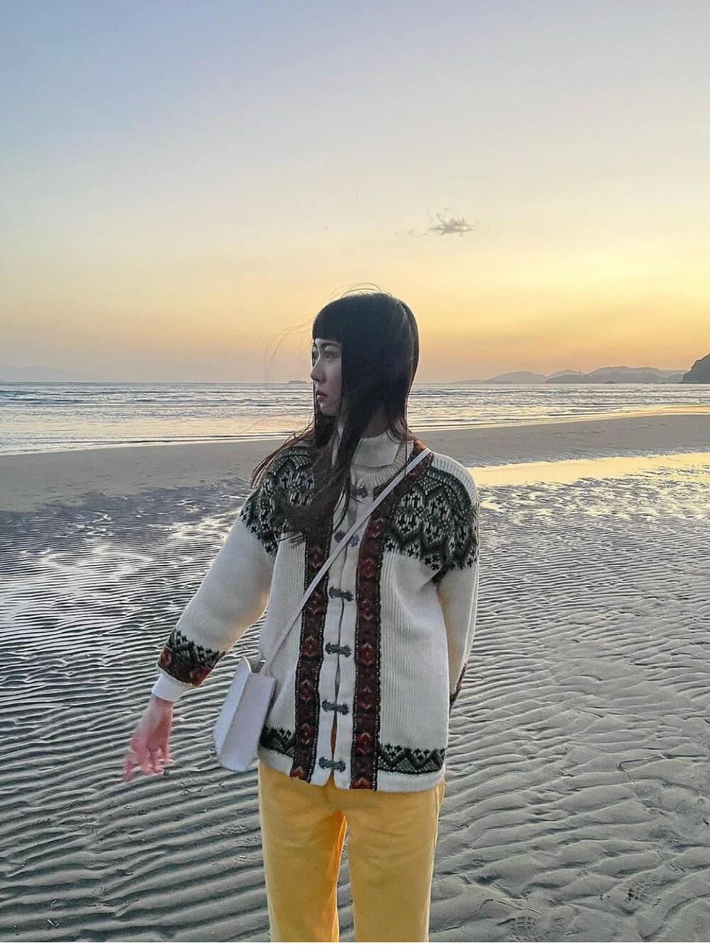 イエロー系のデニムパンツ、ホワイト系のスニーカー、ホワイト系のショルダーバッグを着用したレディースの春コーディネートの4枚目の写真