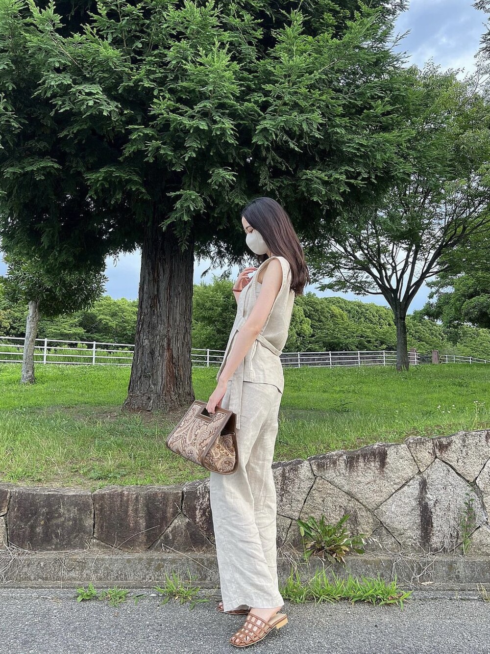 ベージュ系のトップス、ベージュ系のパンツ、ブラウン系のサンダルを着用したレディースの夏コーディネートの2枚目の写真