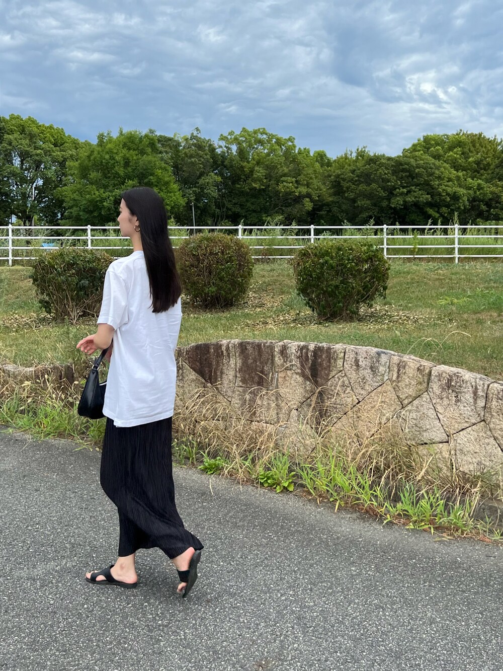 ブラック系のバッグ、ブラック系のスカート、ホワイト系のTシャツ/カットソーを着用したレディースの夏コーディネートの2枚目の写真