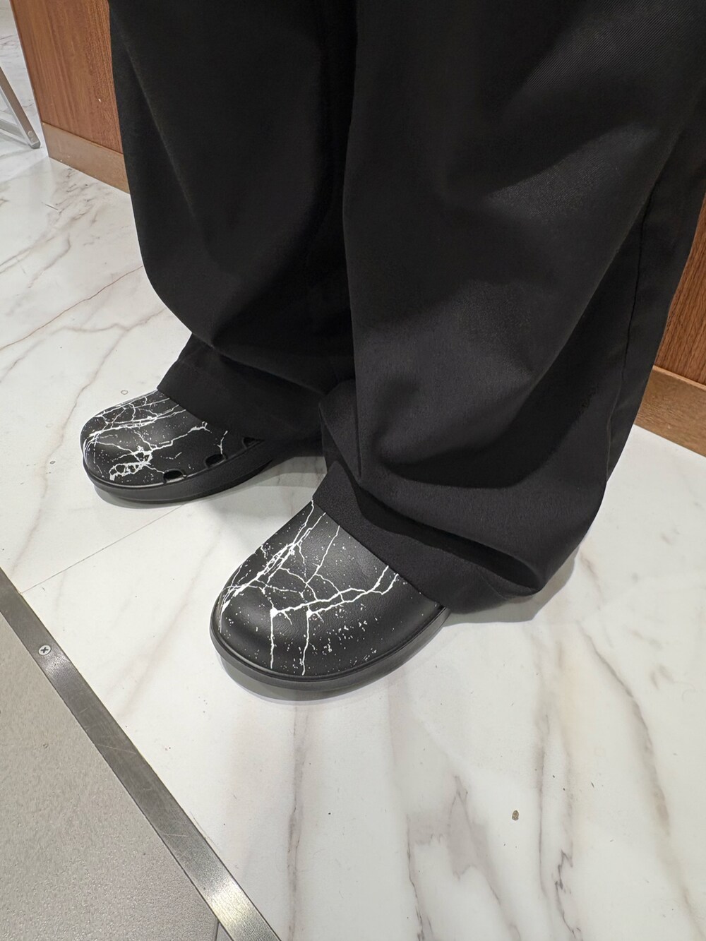 ブラック系のチノパンツ、ブラック系のサンダル、ブラック系のその他アウターを着用したメンズの秋コーディネートの3枚目の写真