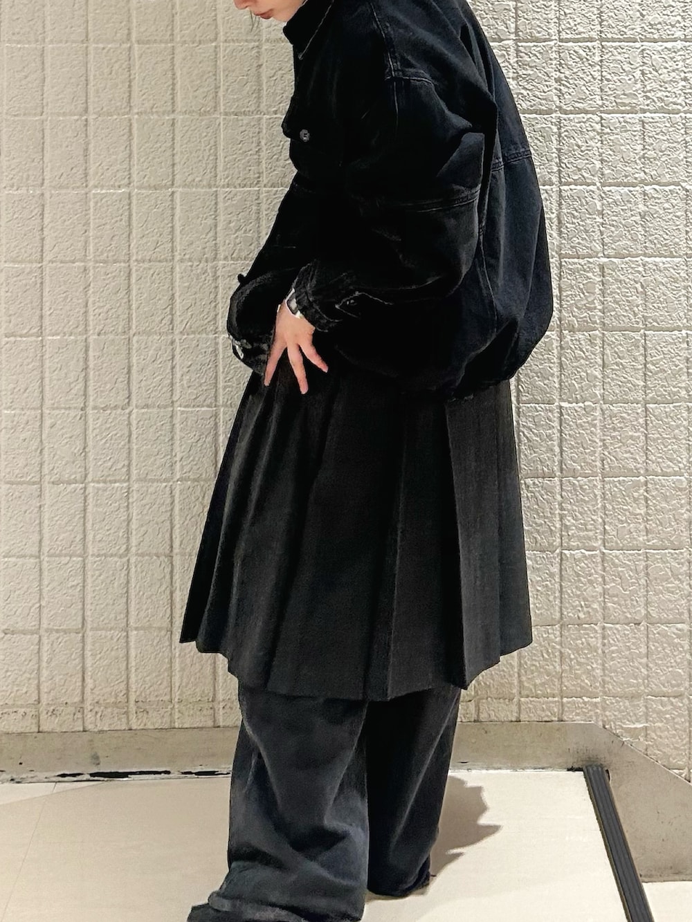 ブラック系のデニムパンツ、グレー系のスカート、ブラック系のカバーオールを着用したレディースの秋コーディネートの3枚目の写真