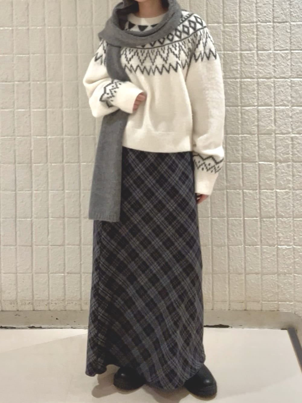 イエロー系のダウンジャケット/コート、ブルー系のスカート、ホワイト系のニット/セーターを着用したレディースの冬コーディネートの4枚目の写真