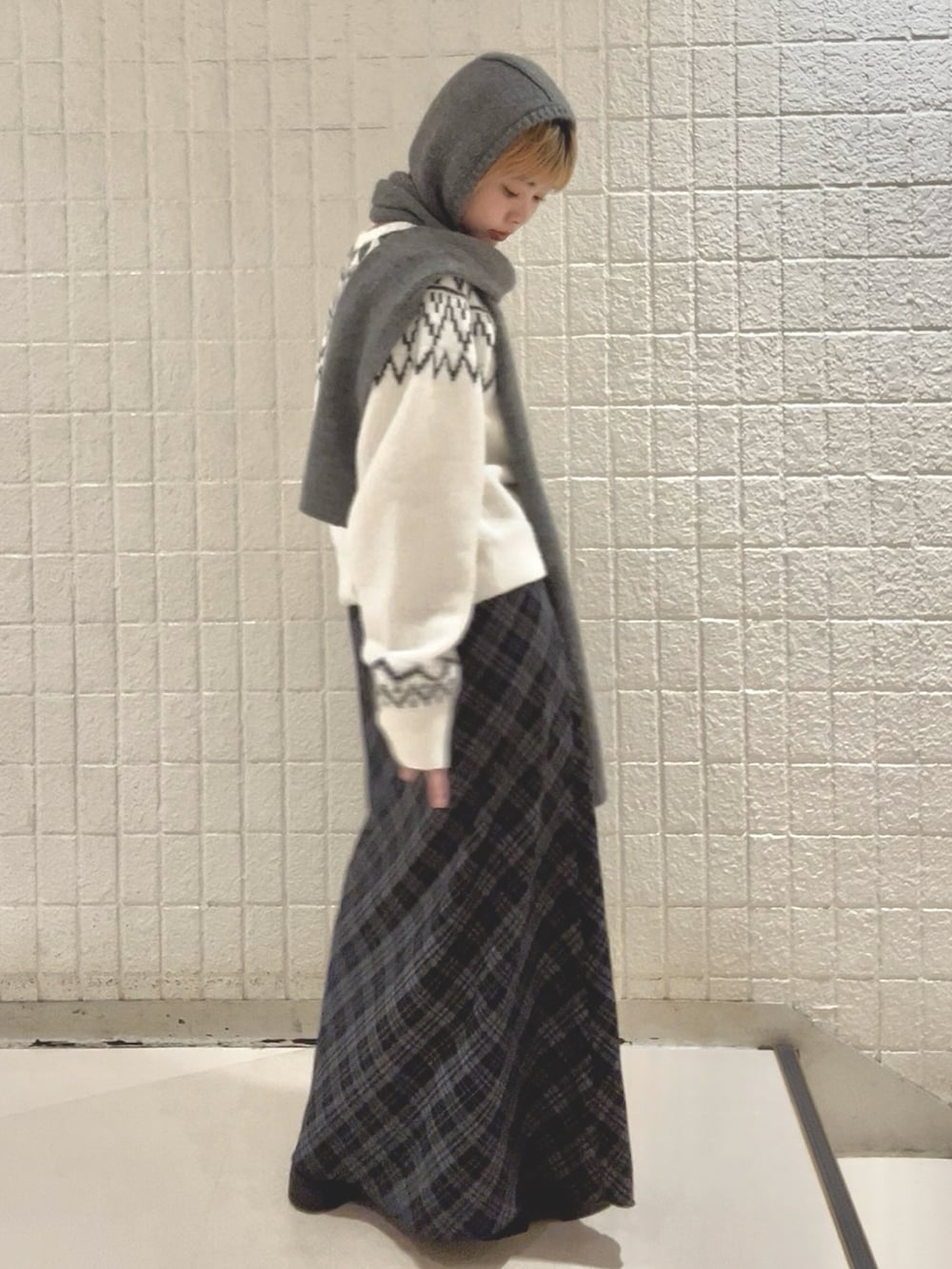 イエロー系のダウンジャケット/コート、ブルー系のスカート、ホワイト系のニット/セーターを着用したレディースの冬コーディネートの3枚目の写真